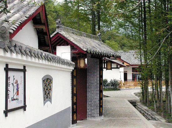 White-walled, tiled-roof buildings beside a narrow paved path and bamboo