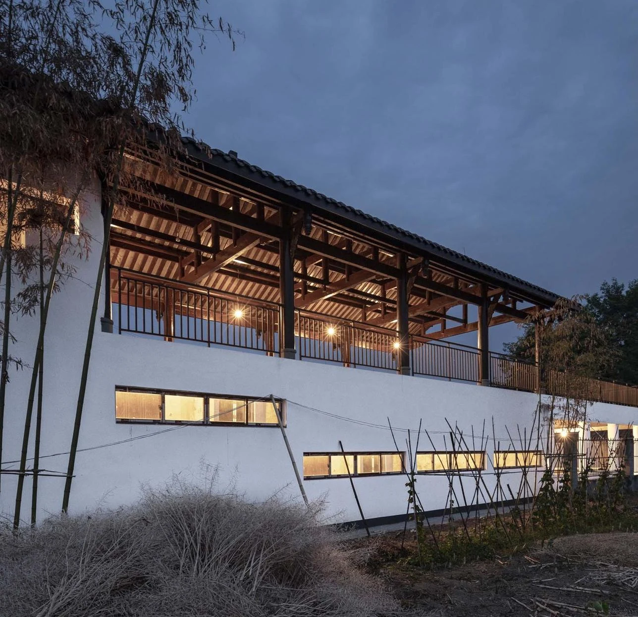 The renewed school at dusk, with an open timber veranda above white walls