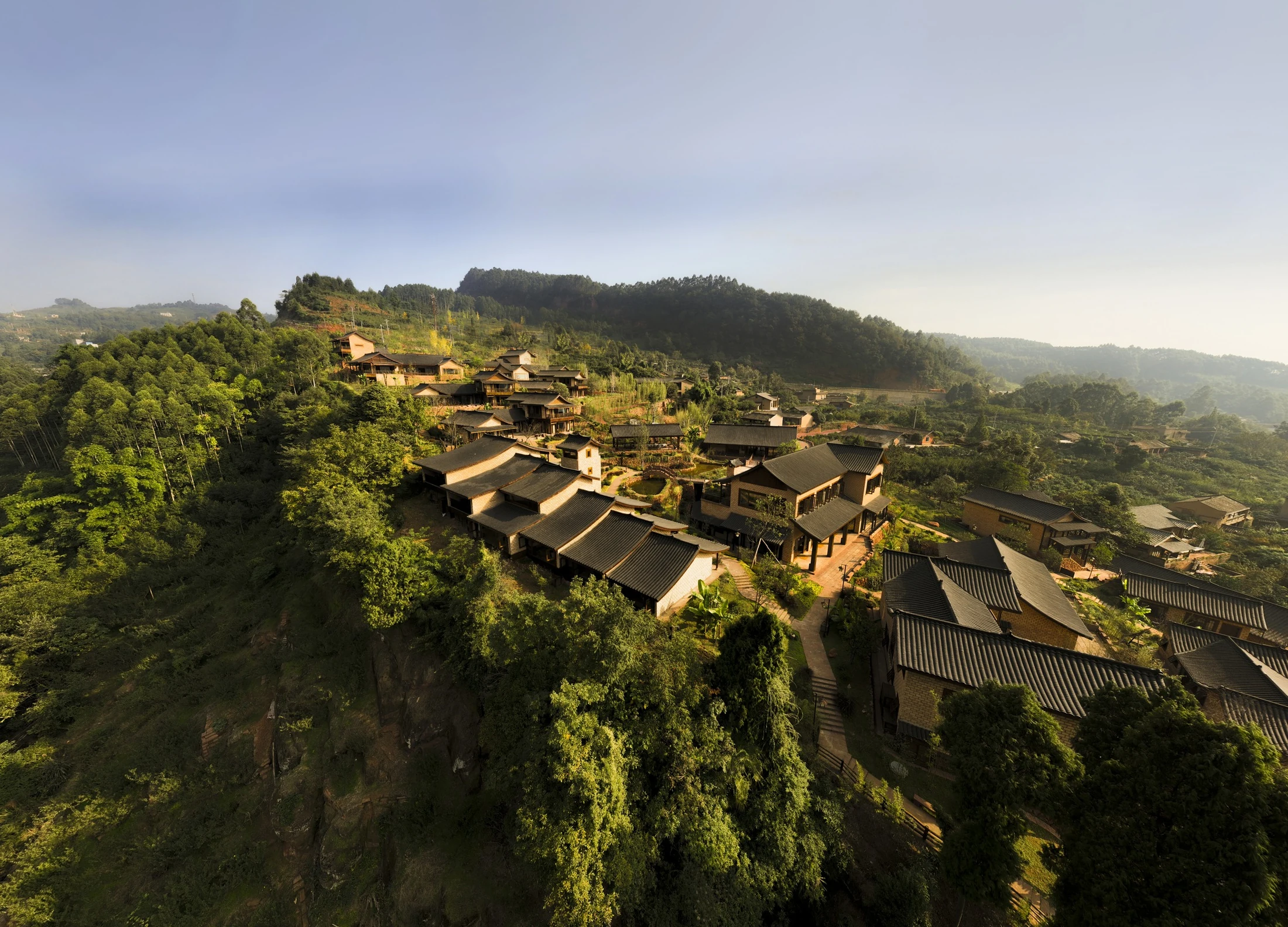 Aerial view of small buildings clustered along the green hillside at Xingfu Ridge